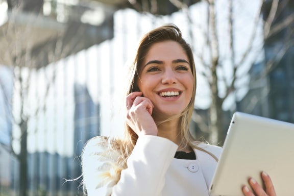Person outside talking on a mobile phone and using a tablet.