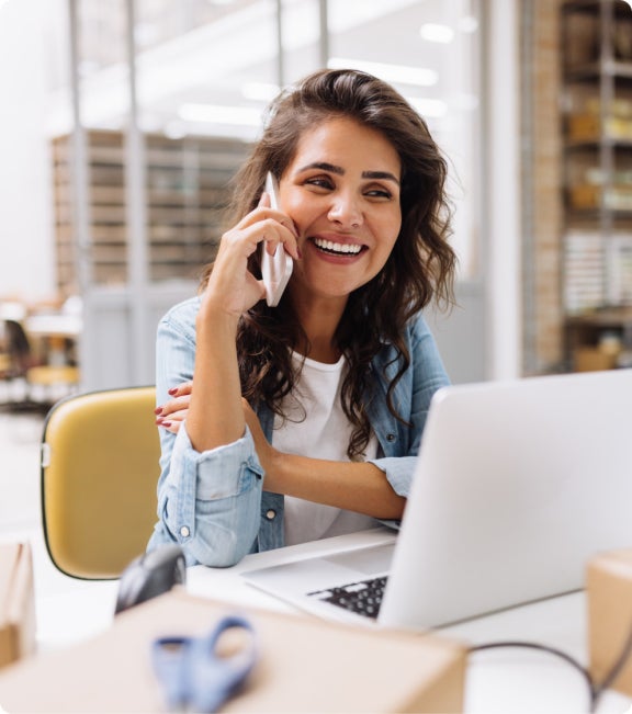 happy woman talking on mobile phone in fron of a laptop