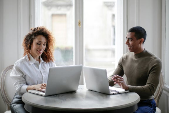 Man and woman using laptops while sitting together at a table