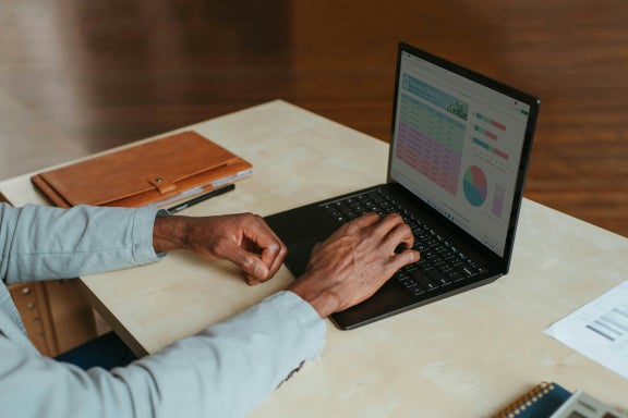 Man adjusting spreadsheets on a laptop.