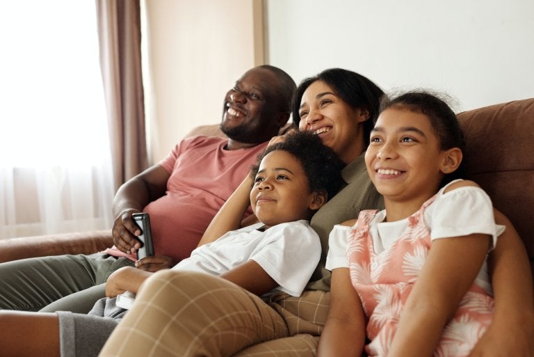 happy family sitting on a couch and watching tv