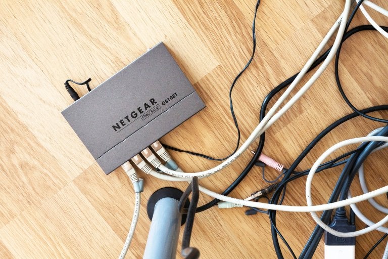 office router sits on a hardwood floor connected to wires