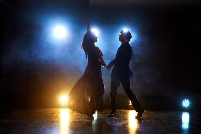 couple dance on stage backlit with lights
