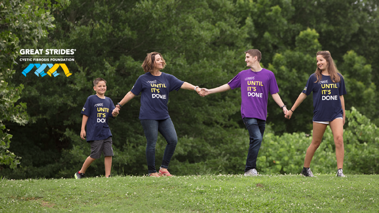 four people walking hand in hand with "I stride until it's done" on their shirts