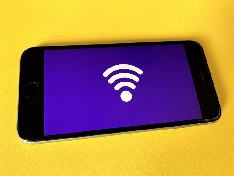 cell phone with a wifi symbol displayed laying on yellow table