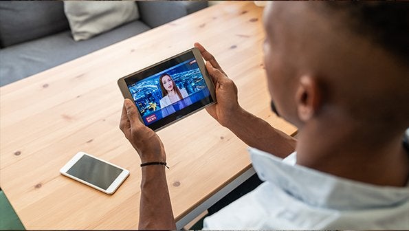 Man watching news broadcast on tablet