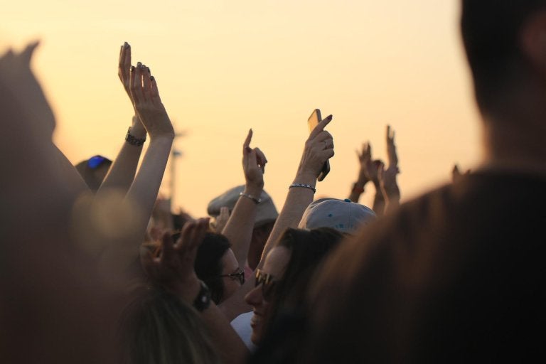photo of crowd at a concert with their hands up