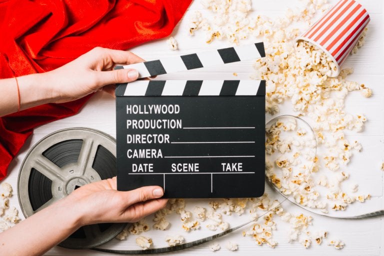photo of movie clackerboard with popcorn and film