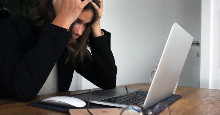 photo of a woman stressed out looking at her laptop overheating