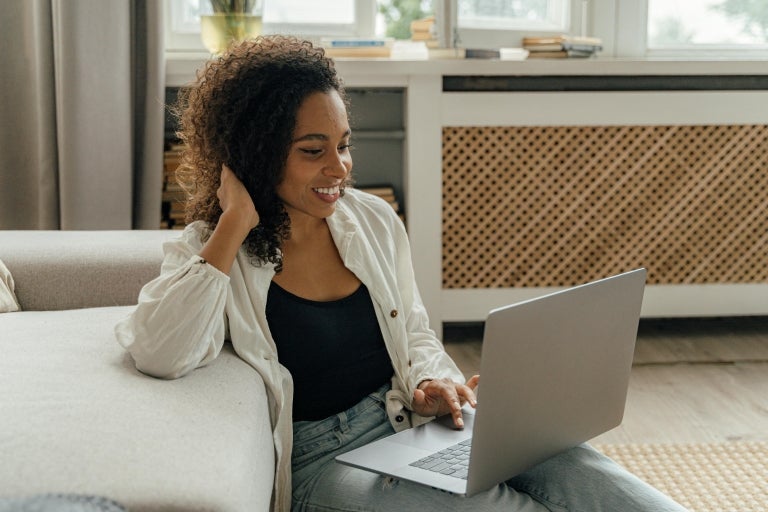 A woman sitting on the floor, using a laptop connected to her home WiFi after installation