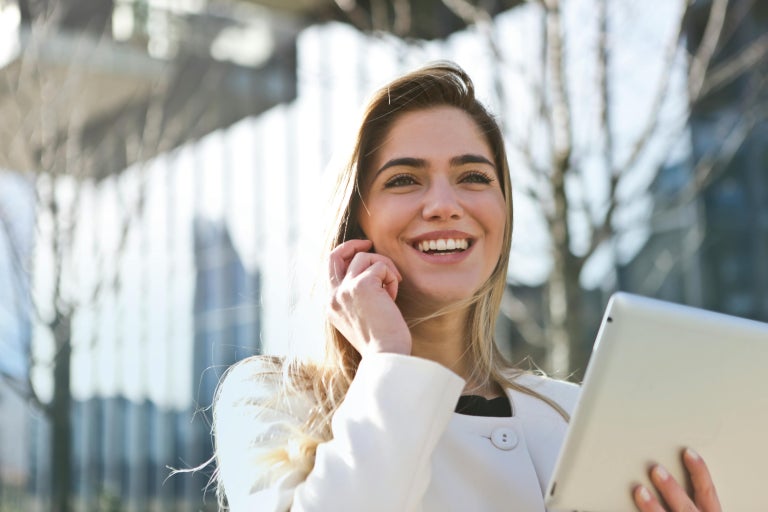 Person outside talking on a mobile phone and using a tablet.