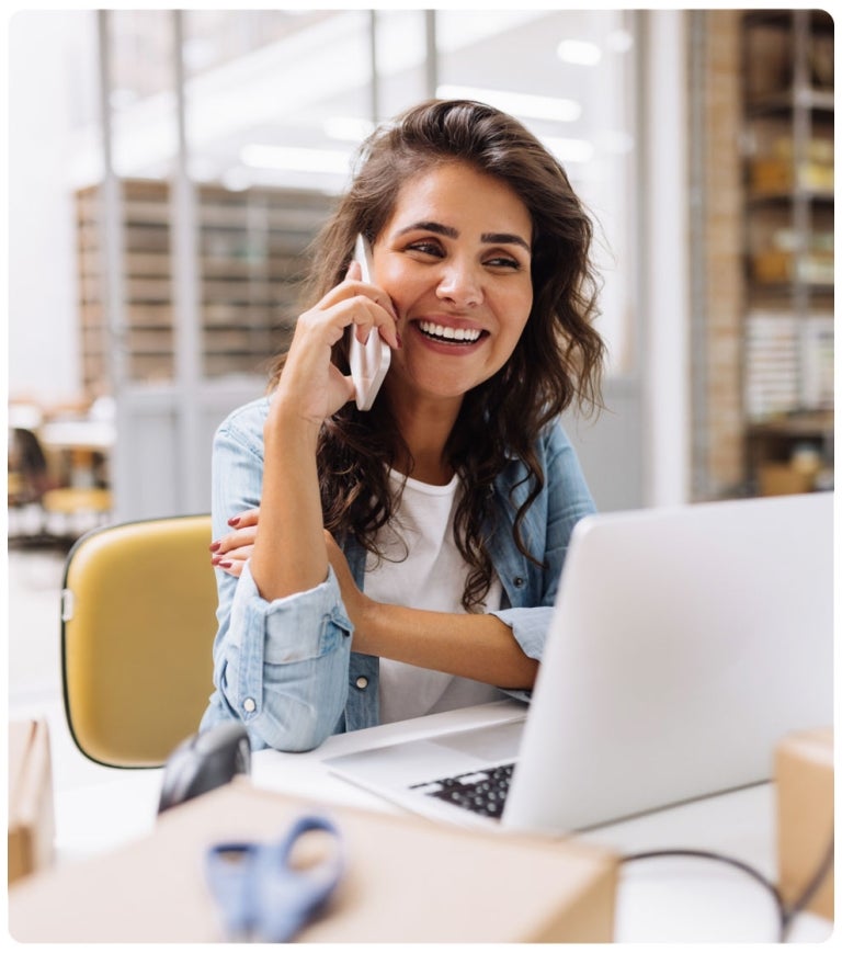 woman on phone sitting at laptop