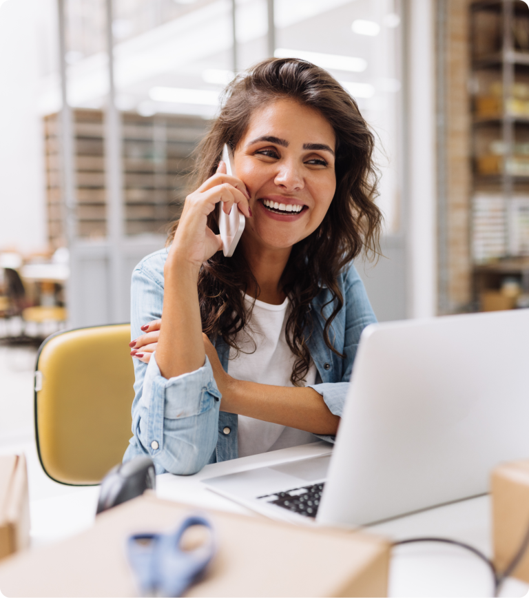 woman on phone sitting at laptop