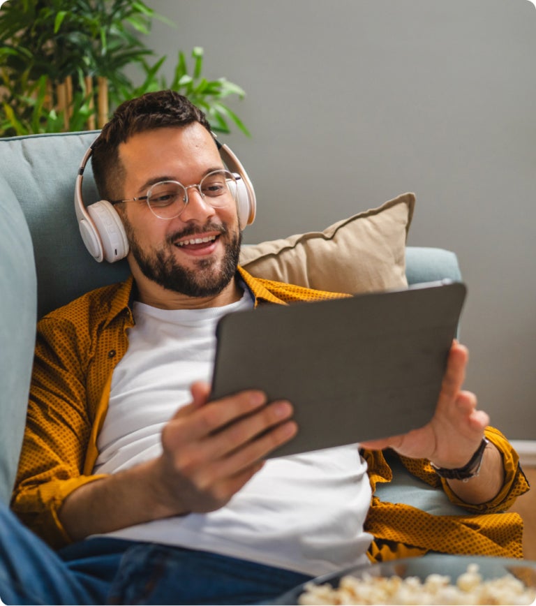 man relaxing in chair using internet on a tablet