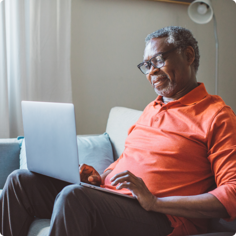 Senior sitting on couch using laptop